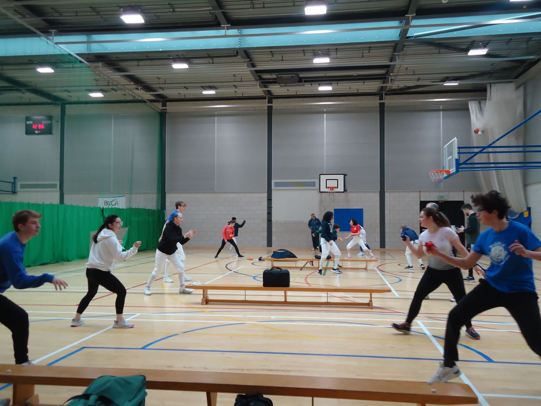 a group of fencers playing games in pairs in a sports hall